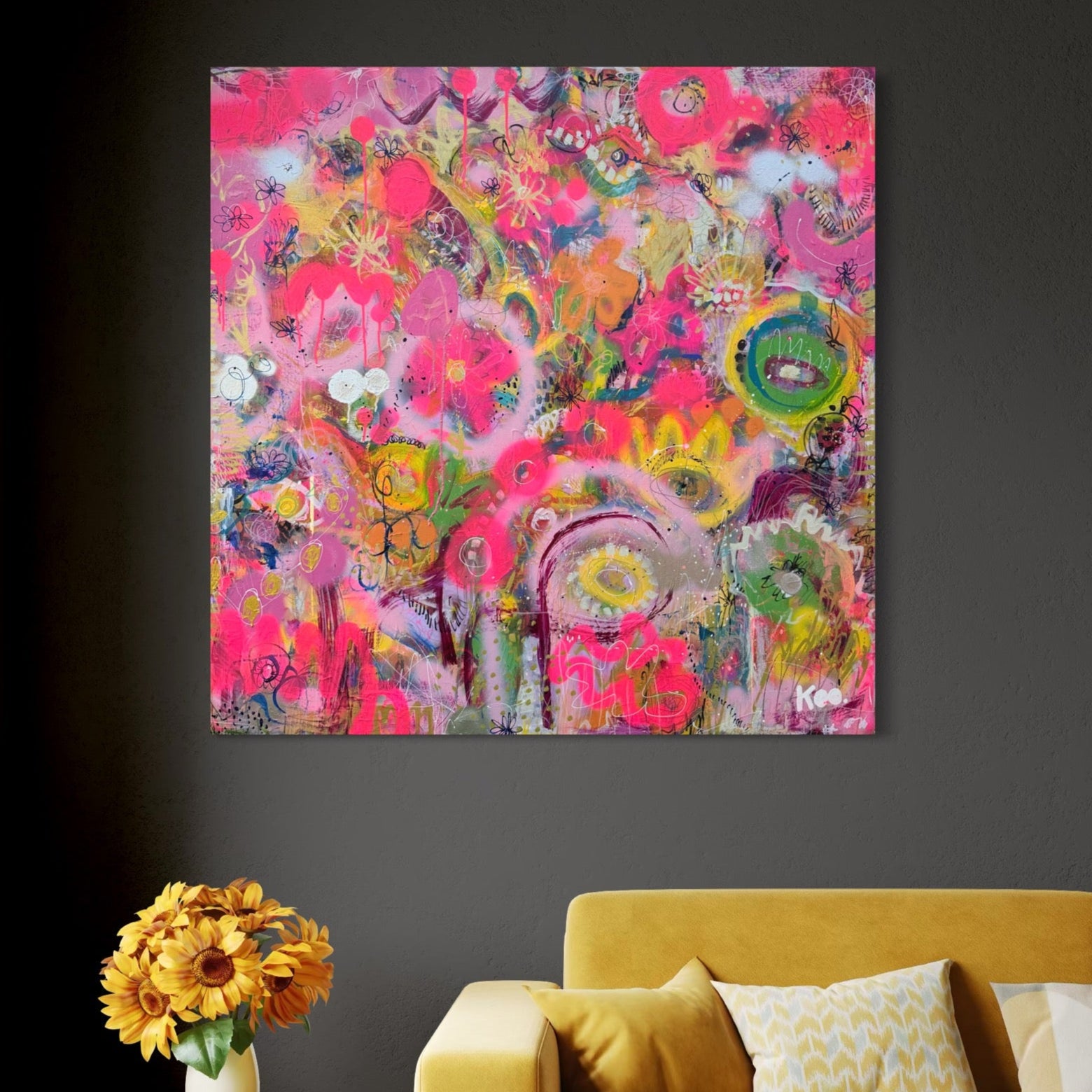Living room with a yellow couch, colorful abstract painting, and small table with flowers.